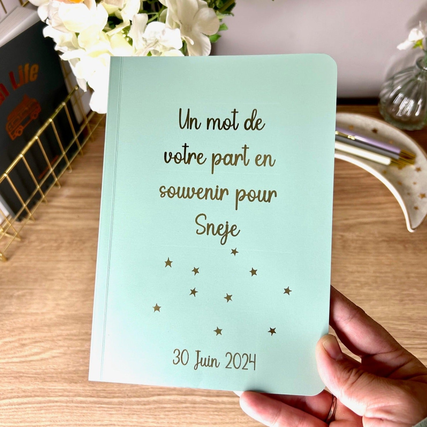 A sage softback notebook that has french text on the cover in gold foil