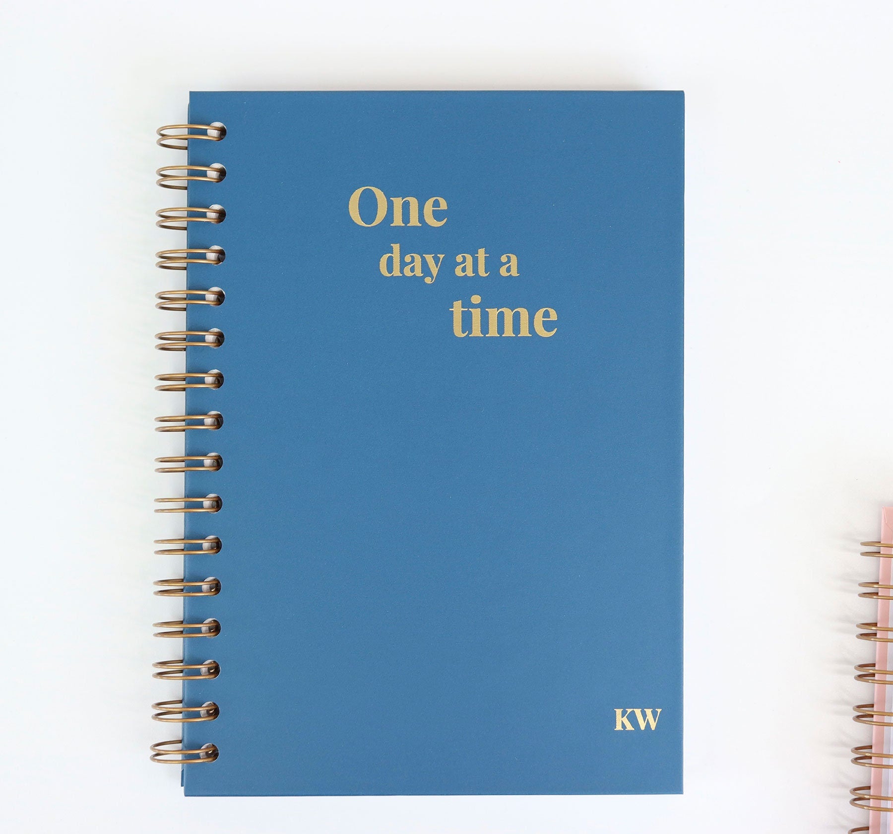 An A5 notebook in Midnight Blue with the words 'One day at a time' in gold foil which is a customers design of sobriety notebook.