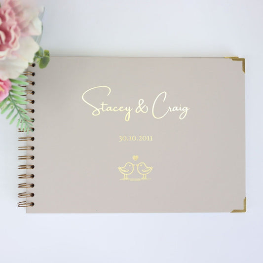 An A4 memory book in stone that says 'Stacey and Craig' with a date underneath and an image of two love birds kissing all in gold foil