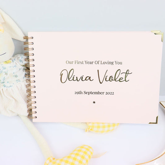 An A4 memory book in Pale Pink with the words 'Our first year of loving you Olivia Violet 29th September 2022' all in gold foil