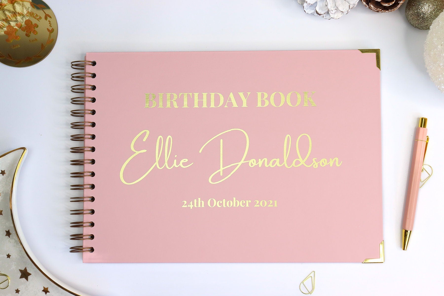 A powder pink birthday book cover with the words 'Biryhday Book Ellie Donaldson 24tg October 2021' in gold foil