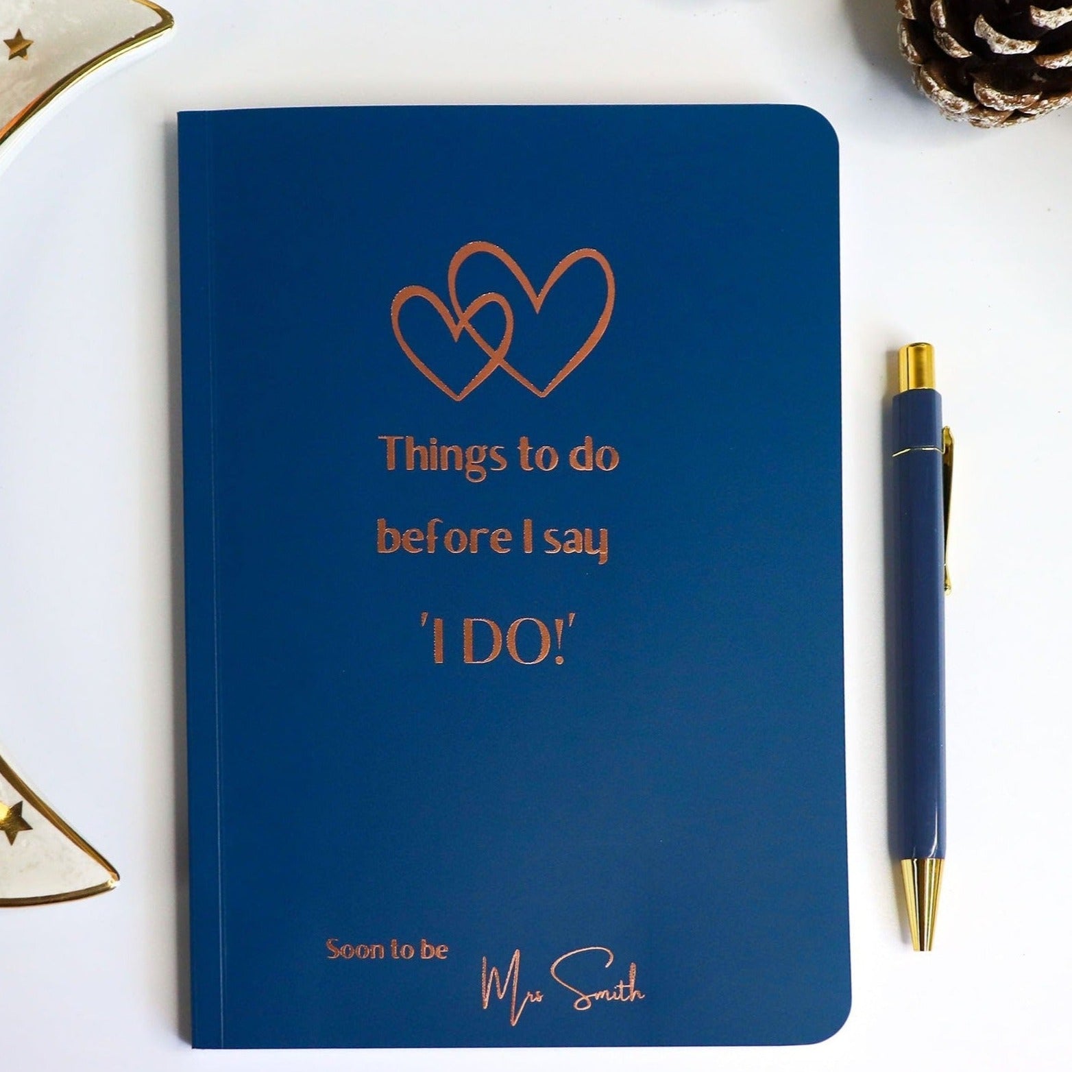 A midnight Blue softback notebook that says 'Things to do before I say I do, Soon to be Mrs Smith' in bronze foil