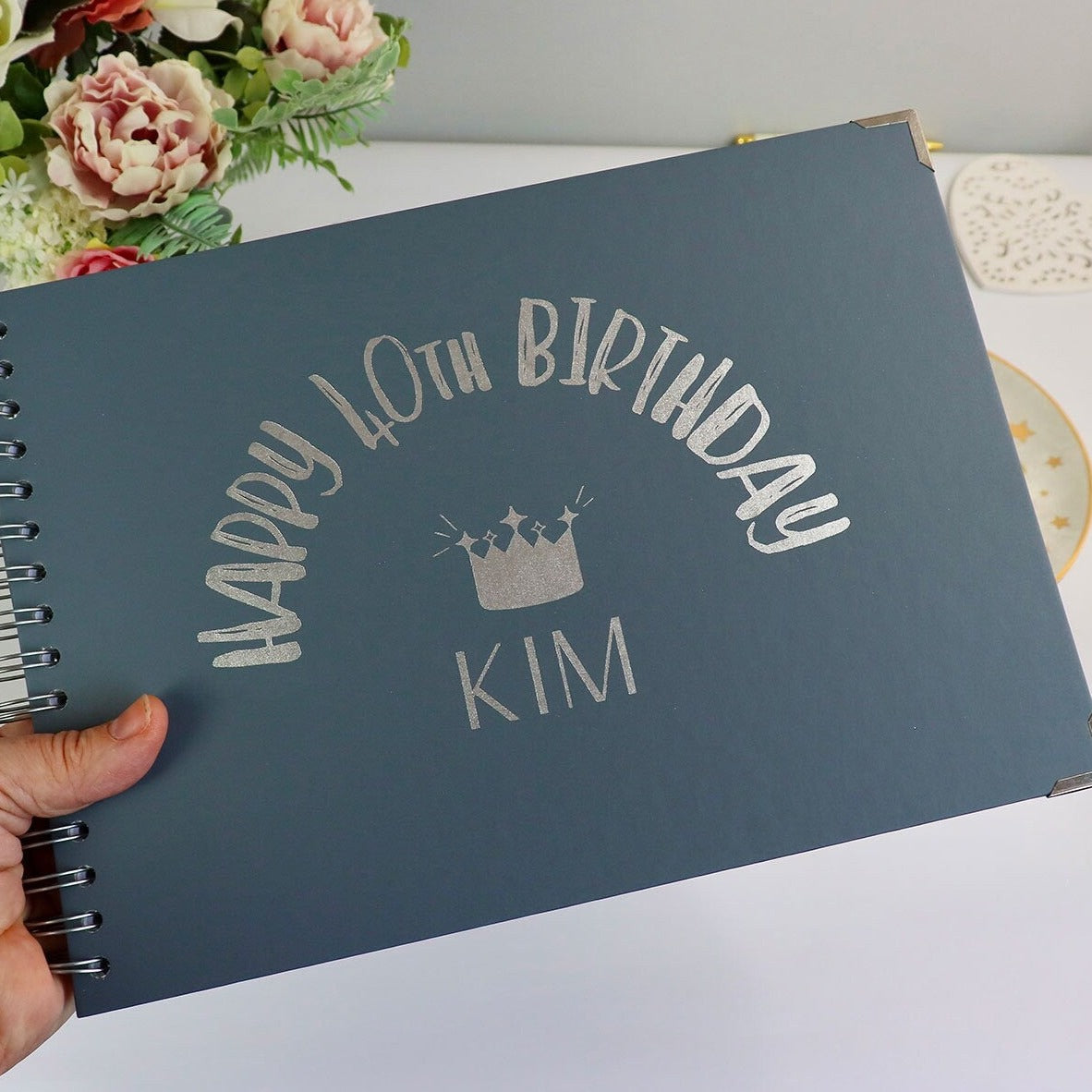 An A4 blue/grey memory book with the words 'Happy 40th birthday Kim' with an image of a crown above the name in silver fo