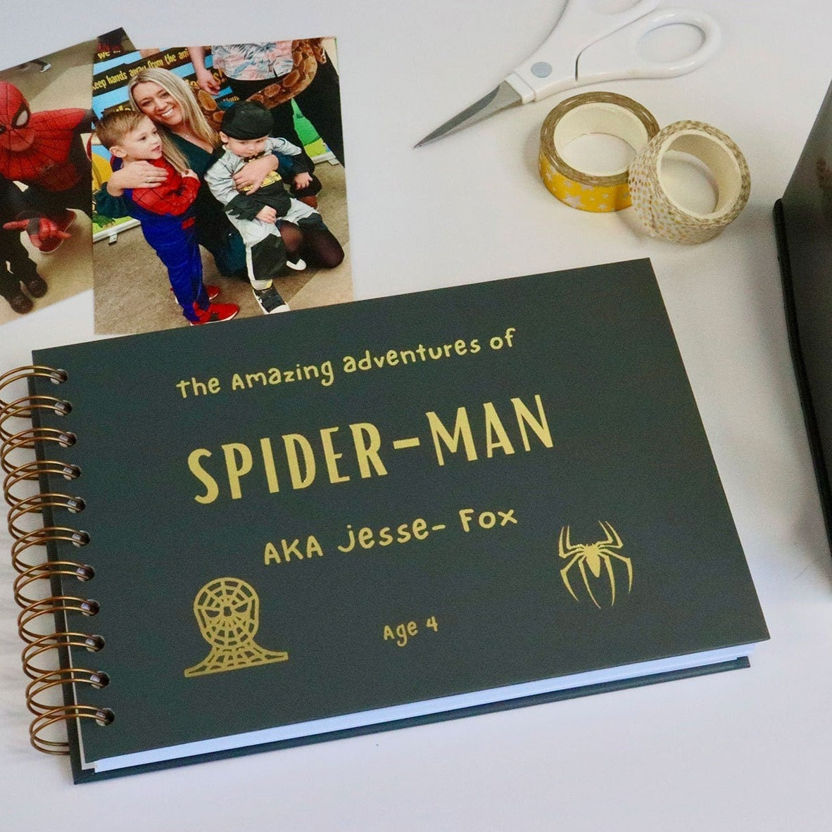 An A5 charcoal kids memory book which says 'The amazing adventures of Spiderman AKA Jesse-Fox' with two images of spiderman all in golf foil.