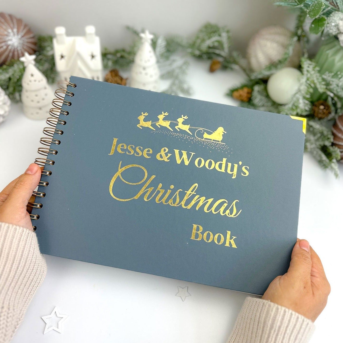 An A4 memory book in Blue/Grey with the words 'Jesse and Woody's Christmas Book' with an image of santa on his reindeer sleigh all in golf foil