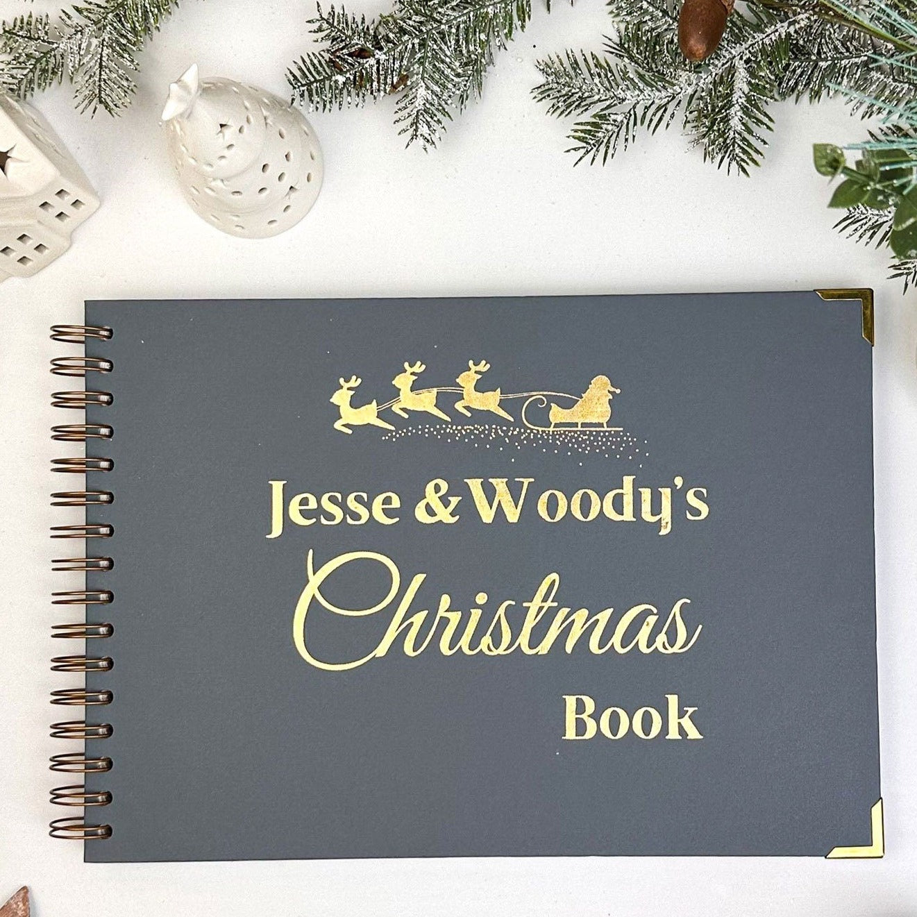 An A4 memory book in Blue/Grey with the words 'Jesse and Woody's Christmas Book' with an image of santa on his reindeer sleigh all in golf foil