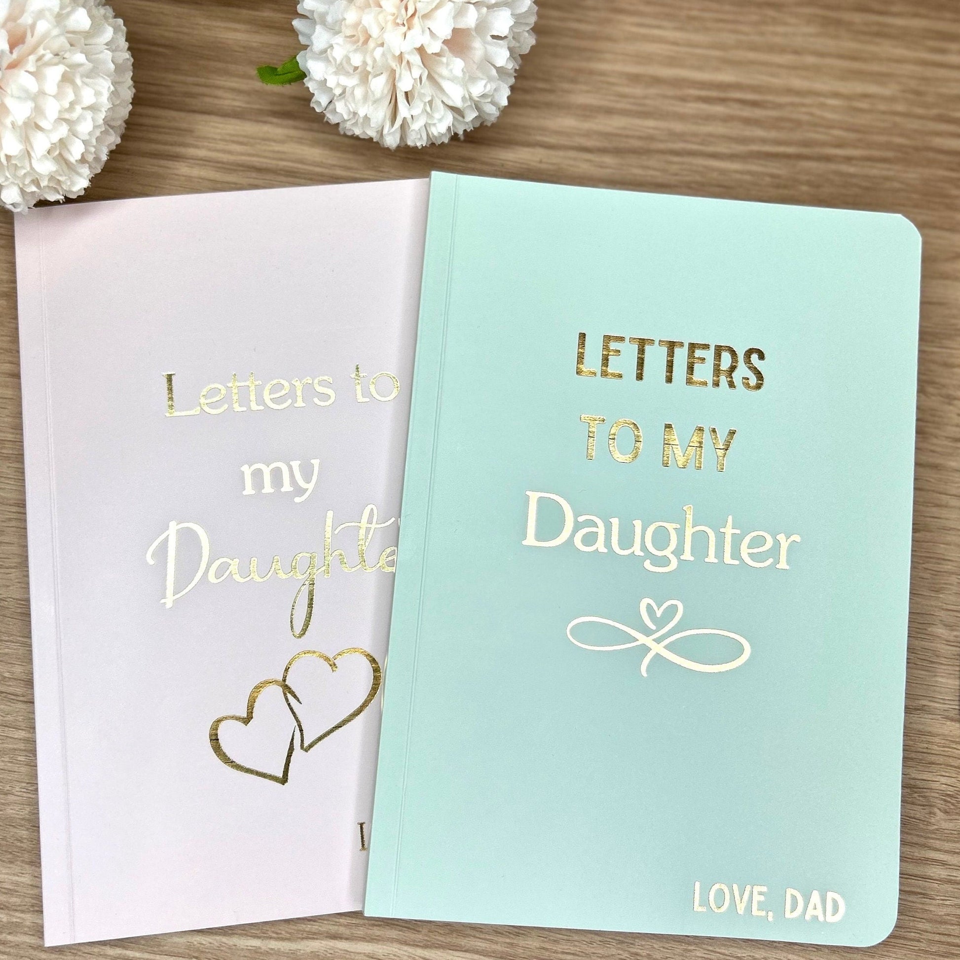 two softback notebooks, one in sage that says 'Letters to my Daughter' and the other one in pink saying 'Letters to my Daughter