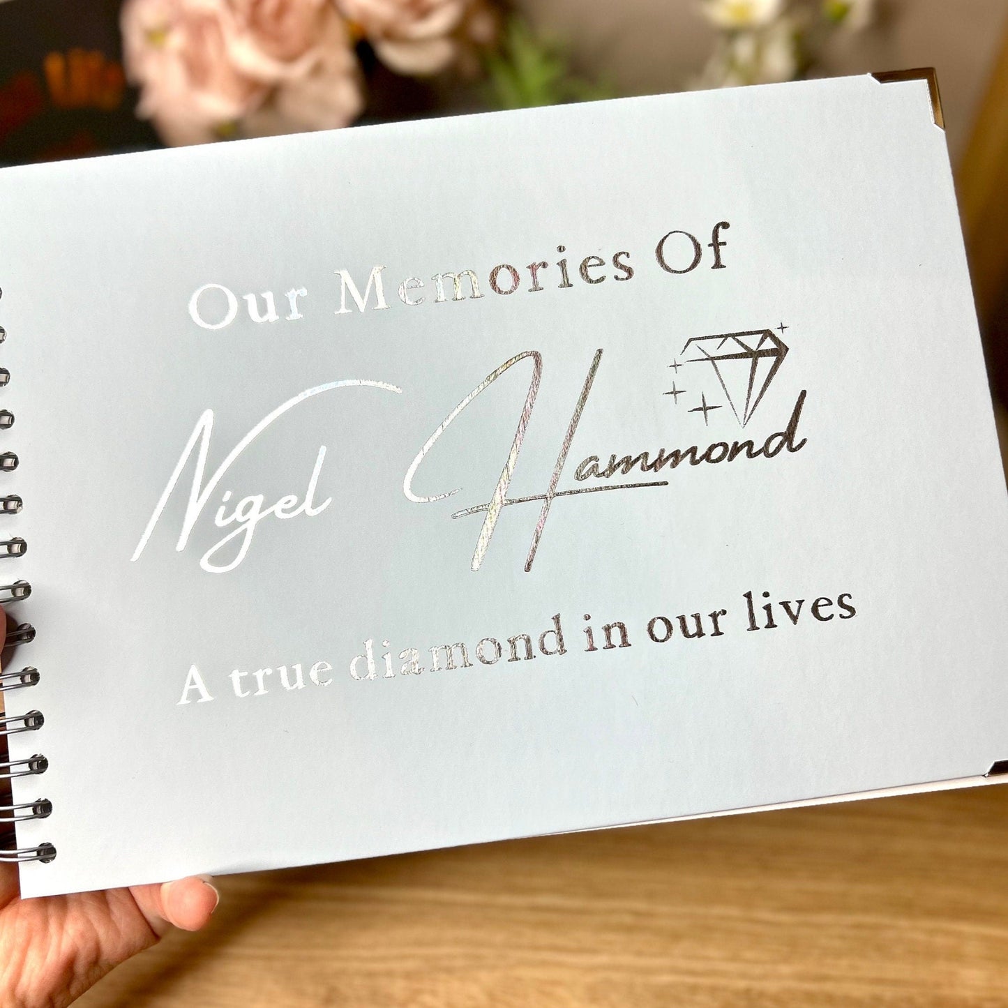 An ice blue memory book with the words 'Our Memories of Nigel Hammond A true diamond in our lives' in silver foiling