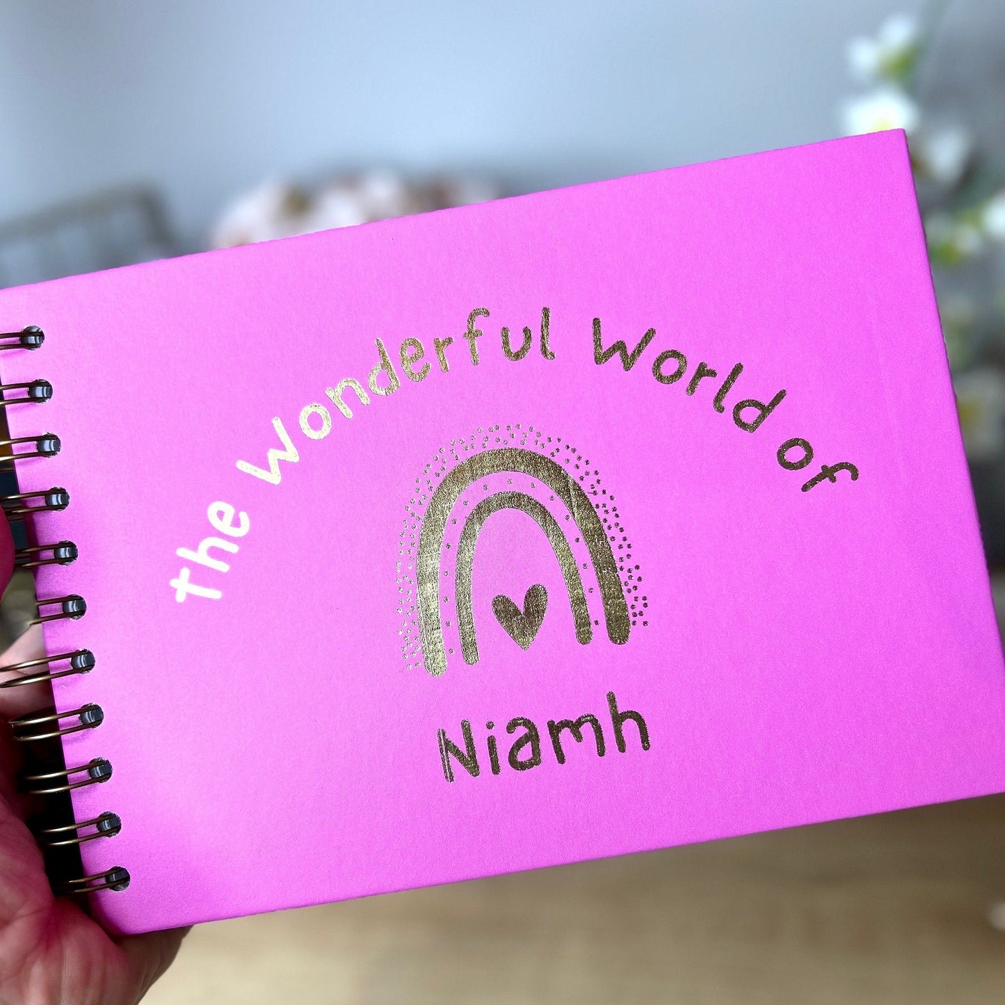 An A5 memory book in Hot Pink that says 'The wonderful world of Niamh with a rainbow all in gold foil