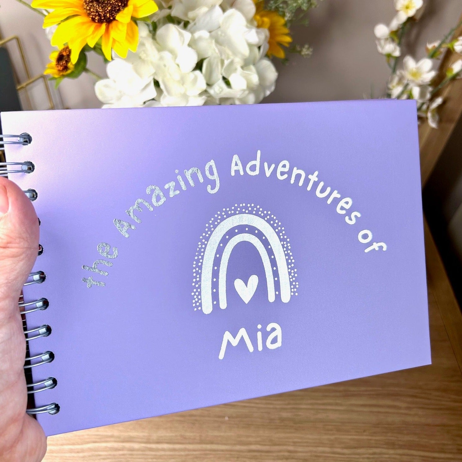 An A5 memory book in Lilac that says 'The wonderful world of Mia with a rainbow all in gold foil