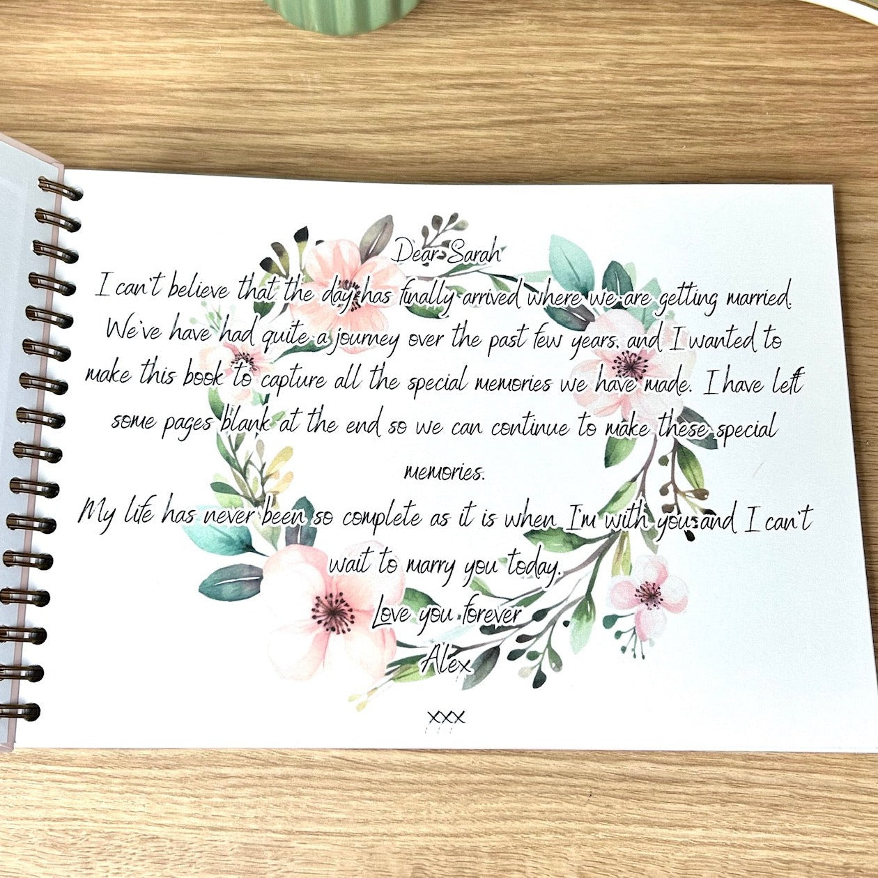The first page of the 'Our story so far' memory book. It is a heart felt love letter to the recipient with a floral wreath printed as a background
