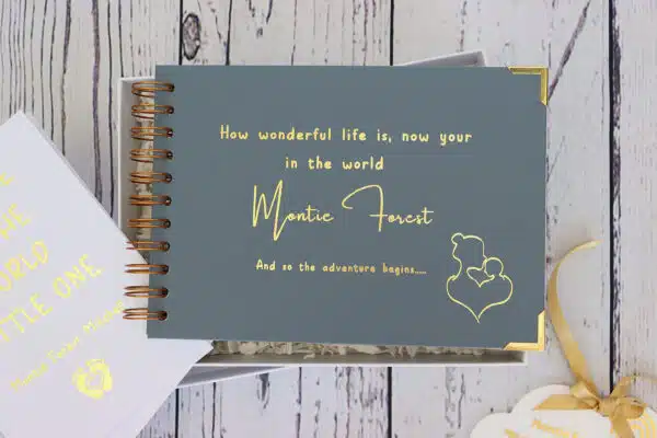 An A5 landscape memory book in blue grey that says How wonderful life is now your in the world Montie Forest in gold foil.